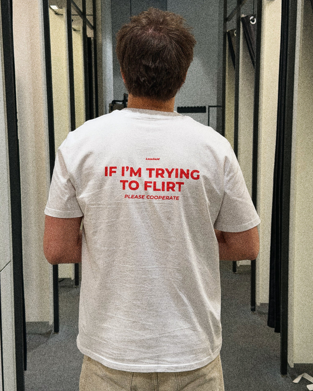 LessSaid "If I’m Trying to Flirt Please Cooperate" humorous graphic t-shirt displayed on a person.