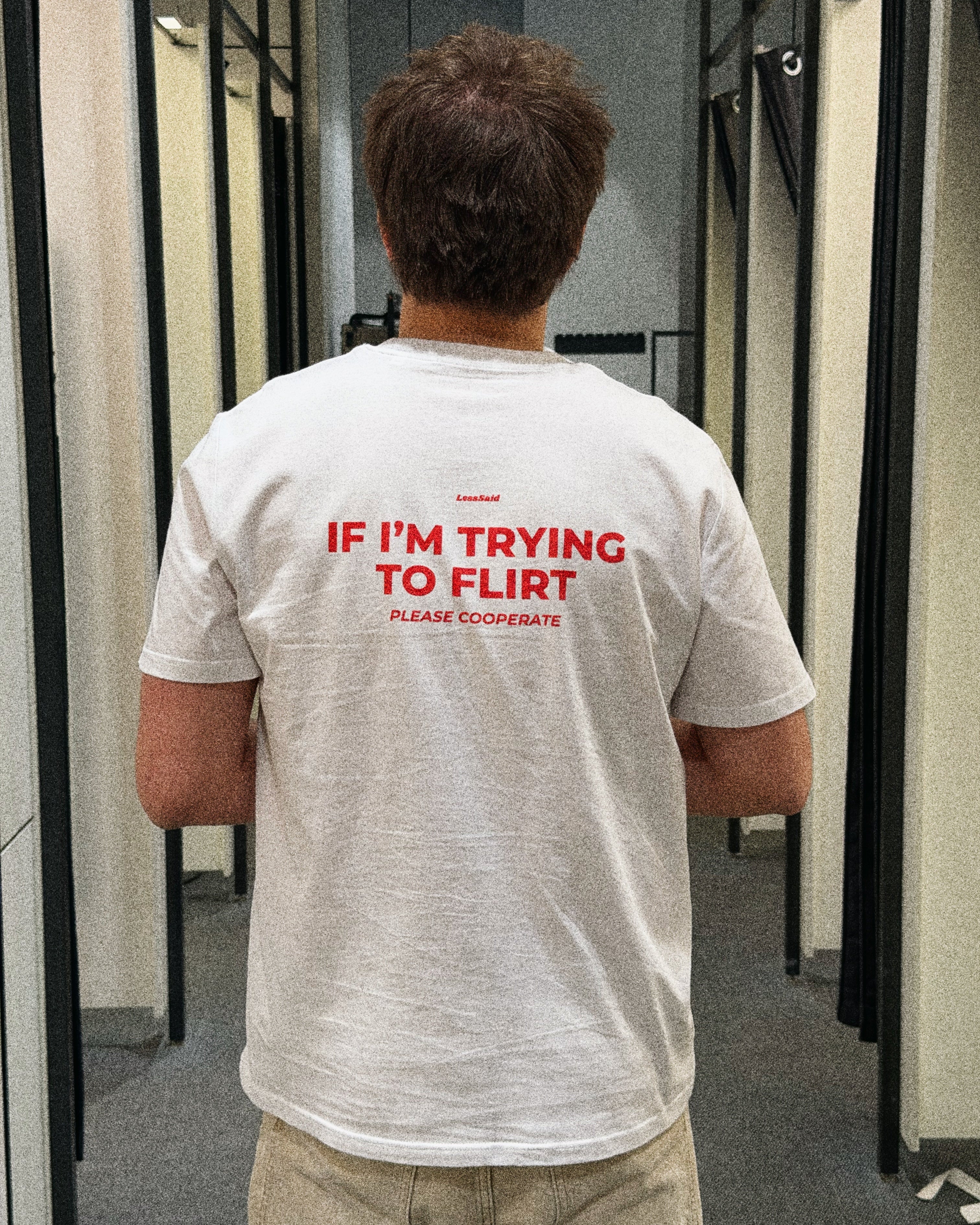 LessSaid "If I’m Trying to Flirt Please Cooperate" humorous graphic t-shirt displayed on a person.