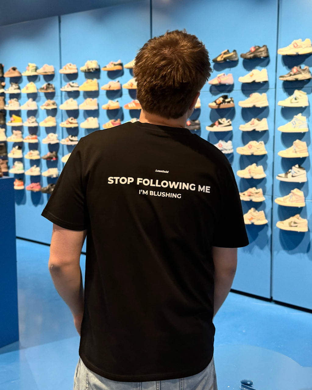 LessSaid "Stop Following Me" graphic hoodie featuring bold text on a comfortable black fabric.